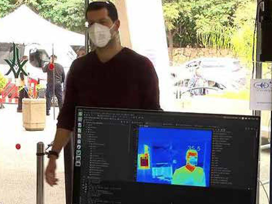 Thermal scanning machine taking a man's temperature as he walks through the entrance